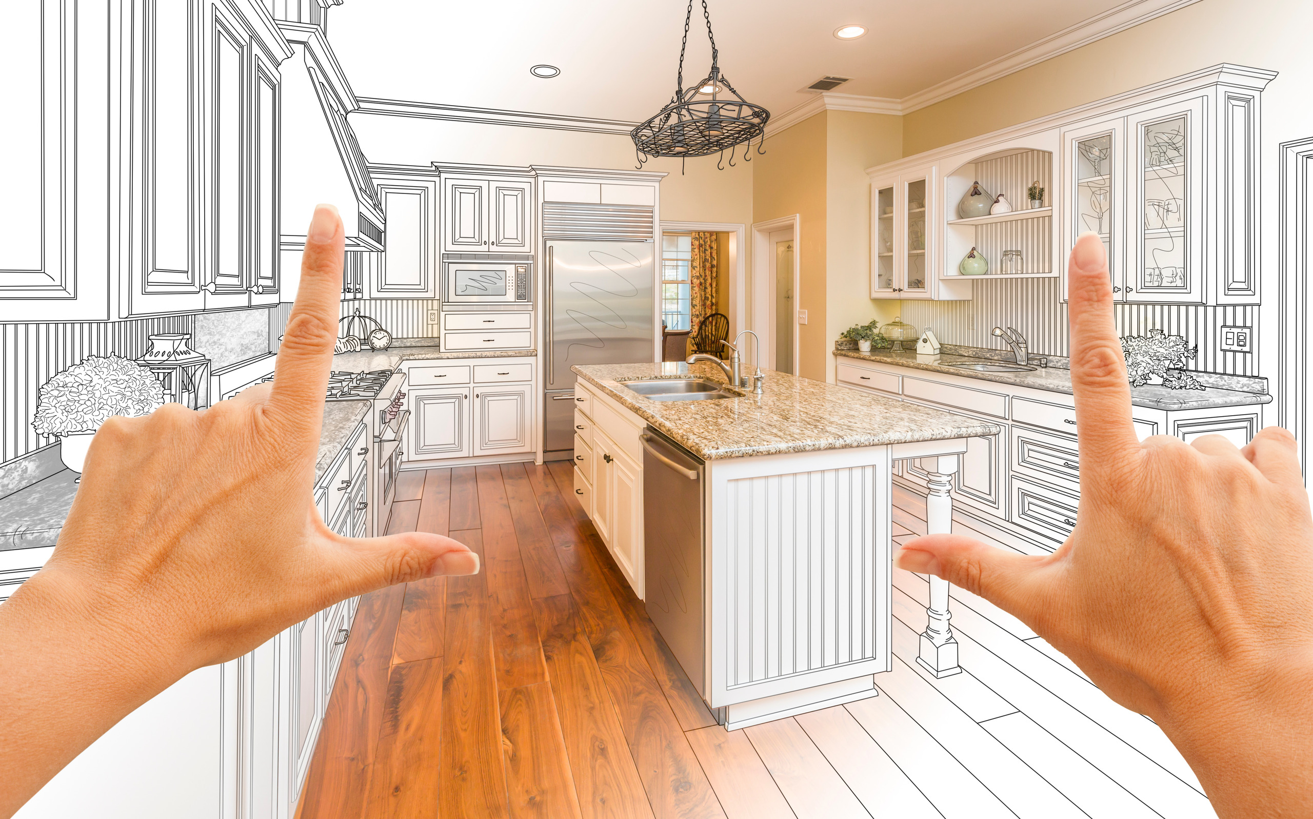 A person uses their hands to frame a kitchen. Elements of the kitchen are black and white blueprints/drawings while other elements, like the kitchen island, are real.